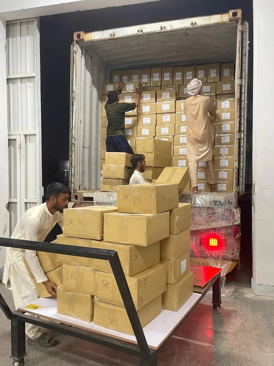 Workers loading cartons of finished textiles into an export container at TABAN Global in Faisalabad, Pakistan